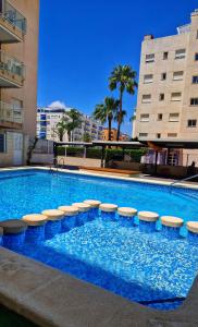 a large swimming pool with stools in front of a building at Chula Vista Apartamento, 200m de la playa, piscina, parking in Daimuz