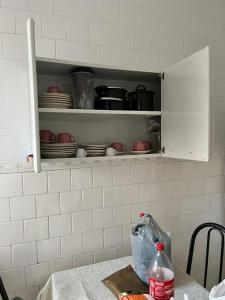 a kitchen counter with a cupboard with dishes on it at Apartamento Centro SerraNegra in Serra Negra