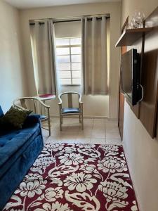 a living room with a blue couch and a tv at Apartamento Centro SerraNegra in Serra Negra