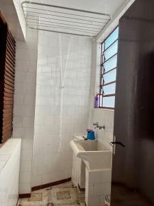 a white bathroom with a sink and a tub at Apartamento Centro SerraNegra in Serra Negra