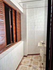 a bathroom with a window and a tub and a sink at Apartamento Centro SerraNegra in Serra Negra