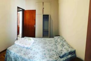 a small bedroom with a bed with a floral bedspread at Apartamento Centro SerraNegra in Serra Negra