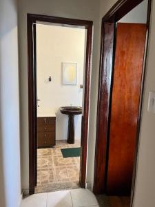 an open door to a bathroom with a sink at Apartamento Centro SerraNegra in Serra Negra