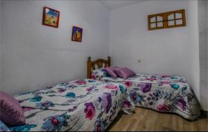 a bedroom with a bed with a floral comforter at La Parrita in Guadalcanal +11 photos