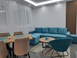 a living room with a blue couch and tables at Apartman NEDA in Banja Koviljača