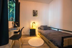 a bedroom with a bed and a desk with a lamp at Maison de ville envoutante, expérience unique ! in Nozay