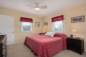 een slaapkamer met een bed met een rode sprei en 2 ramen bij SNH448 L'il Seabreeze in Nags Head