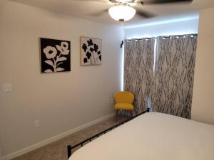 a bedroom with a bed and a yellow chair at The Wildflower at Coventry Rows in Omaha +5 photos