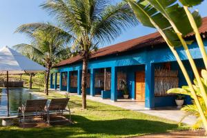 a blue building with palm trees and a pool at Vila Kavaju Preá in Prea