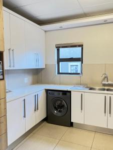 a kitchen with white cabinets and a washing machine at Finagaello at Amfeld apartment by MGP in Windhoek +19 photos