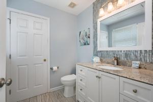 een badkamer met een toilet, een wastafel en een spiegel bij SNH249 SeaAira in Nags Head +38 foto's