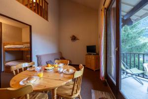 a dining room with a wooden table and a balcony at Rive Tranquille - WIFI - Parking - Plan d'eau in Jausiers