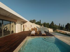 a swimming pool with a wooden deck and a house at Petroto Sea View Villas in Tsoukalades