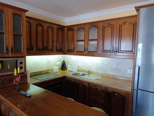 a kitchen with wooden cabinets and a refrigerator at Casa Los Dises in Caleta de Caballo