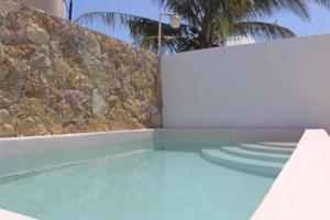 a swimming pool next to a stone wall at La conchita de sisal 3 in Sisal