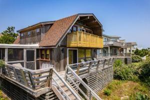 Cette maison en bois dispose d'une terrasse et d'un balcon. dans l'établissement OSF24 Dunesbury, à Corolla