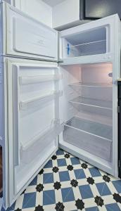 einem leeren Kühlschrank mit offener Tür auf einem karierten Boden in der Unterkunft Le Cozy Nest in Alfortville