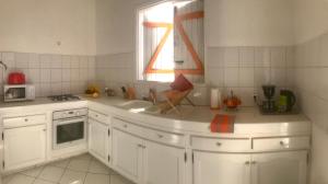 a kitchen with white cabinets and a sink and a window at Kaz a Béa - T3 climatisé avec citerne tampon - gare maritime in Saint-François