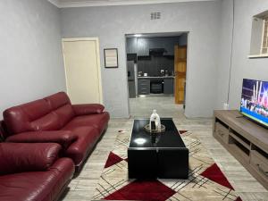 a living room with a leather couch and a table at Amari Cottage in Boksburg