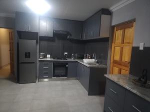 a kitchen with gray cabinets and a light on the ceiling at Amari Cottage in Boksburg