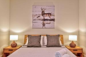 a bedroom with a bed with two lamps and a painting at Verbier C - Mont-Tremblant Pool Spa and Gym in Mont-Tremblant +27 photos