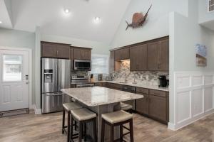a kitchen with wooden cabinets and a large island with bar stools at NH387B Ocracoke Cottage in Nags Head