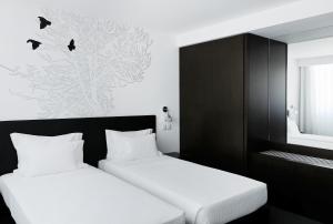 duas camas num pequeno quarto com preto e branco em Open Village Sports Hotel & Spa Club em Guimarães