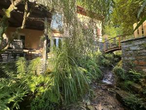 a house with a bridge over a stream in a garden at Casa sul ruscello - piano terra Casa Gauguin in Arcegno