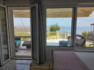 a room with sliding glass doors with a view of the ocean at Baso Hilltop Apartment 3 in Argassi