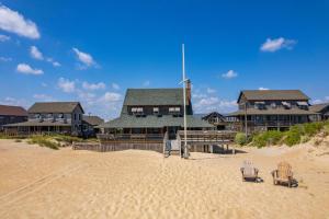 ein Haus am Strand mit zwei Stühlen im Sand in der Unterkunft NH315 Serenity by the Sea in Nags Head