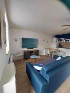 a living room with a blue couch and a tv at Maison Bretonne avec piscine in Marzan