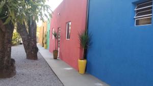 a red and blue building with potted plants on a sidewalk at Bee Hotel Itatiba in Itatiba