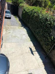 Una acera al lado de un seto con un coche encima. en Alojamiento tipo Cabaña, rodeado de Bosque, en Ciudad de México