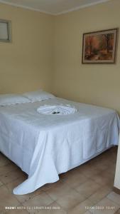 a bed with white sheets and a picture on the wall at Hotel Vale Das Serras in Jacobina