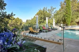 a patio with chairs and umbrellas next to a pool at Mas des Marcellines in La Bouilladisse