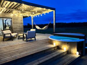 FresnesにあるGreenWoods Ecolodge - Zoo de Beauval et Châteaux de la Loireのハンモックとテーブルと椅子のあるデッキ