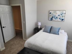 a white bed with blue pillows in a bedroom at The Cottonwood at Coventry Rows in Omaha