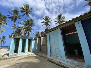 a blue building on the beach with palm trees at Islas de Guna Yala Cabaña tradicional Guna Tubasenika in Arritupo Número Dos