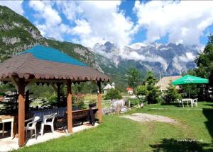 a gazebo with a table and chairs and mountains at Zariklis in Theth