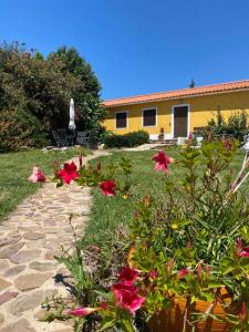 a garden with red flowers and a yellow building at Quinta Cunte - Casa Girassol in São Luis
