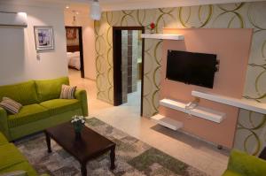 a living room with a green couch and a flat screen tv at Holiday Season in Tabuk