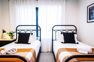 two beds in a small room with white curtains at Tucker's Place in Revelstoke