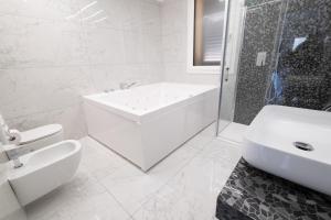 a white bathroom with a tub and a sink at MirabiLuxury in Borgo Fosso Ghiaia