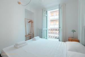a white bedroom with a white bed and a window at Odissea House in Turin