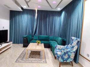 a living room with a green couch and a table at فيلا وشاليه فيينا in Al Qasţal