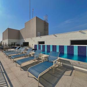 a row of chaise lounge chairs next to a swimming pool at Studio Prime 1510 - Higienópolis in Sao Paulo