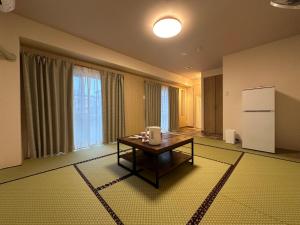 a living room with a table and a refrigerator at 駅本ビルホテル2階 in Yuzawa