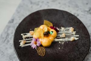 a dessert on a black plate with flowers and nuts at Radisson Blu Hotel, Glasgow in Glasgow