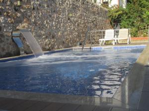 a swimming pool with a water fountain and two chairs at Sabah Pansiyon in Antalya