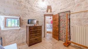a room with a tv on a wooden dresser with a window at Trullo Matilde in Martina Franca